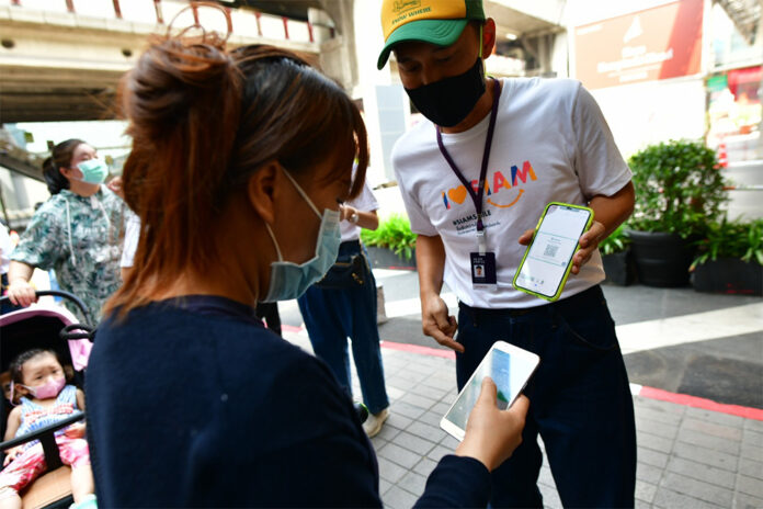 A customer at Siam Paragon uses her phone to scan the QR code logging her visit with a government website on May 17, 2020.