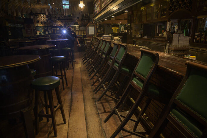 In this April 21, 2020, file photo, a security guard is seen walking a round of patrol in the empty interior of Mulligan's, a popular Irish bar on Khaosan Road. Photo: Sirachai Arunrugstichai
