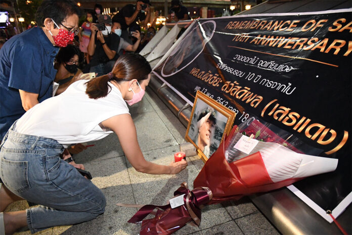 Khattiyah Sawasdipol lights a candle during a candlelit vigil for her father in front of an entrance of MRT Lumphini on May 13, 2020.