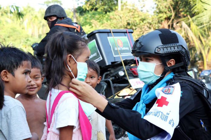 A member of paramilitary rangers in Narathiwat province puts on a face mask to a girl during a humanitarian operation on May 11, 2020.