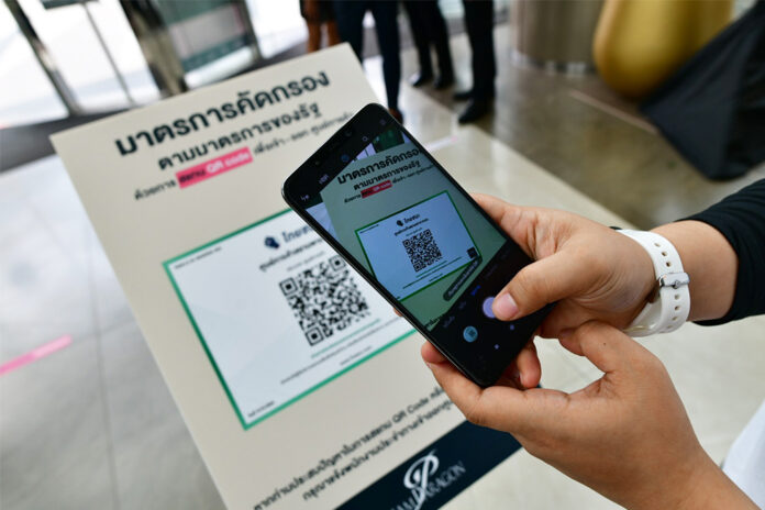 A customer at Siam Paragon uses her phone to scan the QR code logging her visit with a government website on May 17, 2020.