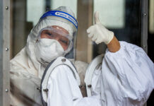 3 New Infections Confirmed, Gov’t Plans More Venue Reopenings A health worker in protective clothing gives thumbs up from behind a plastic partition as she prepares to collect nasal swab samples to test for the coronavirus in Bangkok, Thailand, Wednesday, May 6, 2020. Photo: Gemunu Amarasinghe / AP