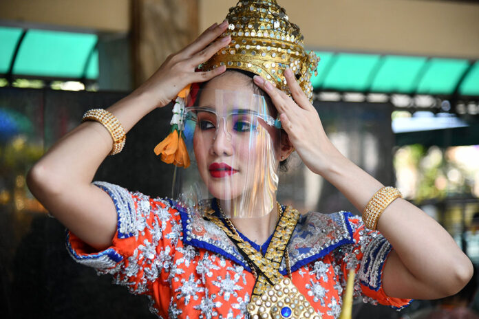 A dancer at the Erawan Shrine puts on a face shield along with her Thai dance head ornament on May 5, 2020.