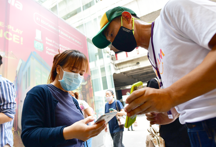 A customer at Siam Paragon uses her phone to scan the QR code logging her visit with a government website on May 17, 2020.