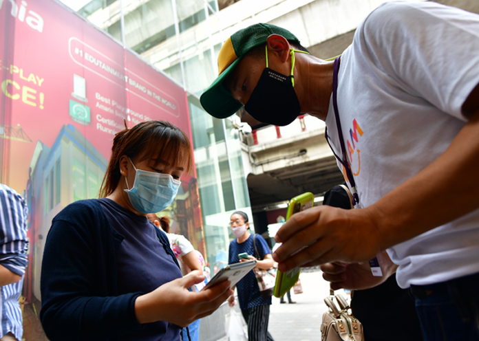A customer at Siam Paragon mall checks in via a government website on May 17, 2020, the first day malls are allowed to reopen.