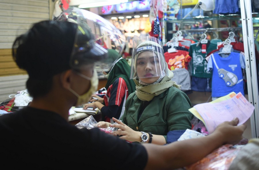 A saleswoman wearing a face shield is pictured in a shop at the Tanah Abang textile market in Jakarta, Indonesia, June 15, 2020. Photo: Zulkarnain / Xinhua