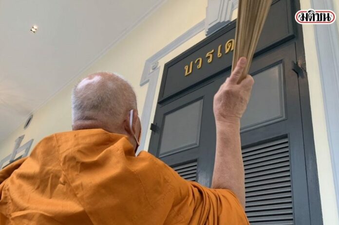A monk sprinkles holy water on the door of Boworadet Room inside the army headquarters on June 24, 2020.