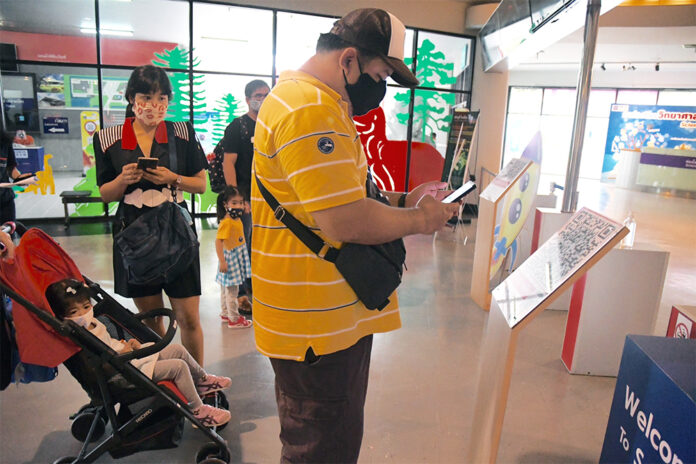 A man uses his phone to scan the QR code logging his visit to a museum with a government website. A man uses his phone to scan the QR code logging his visit to a museum with a government website.