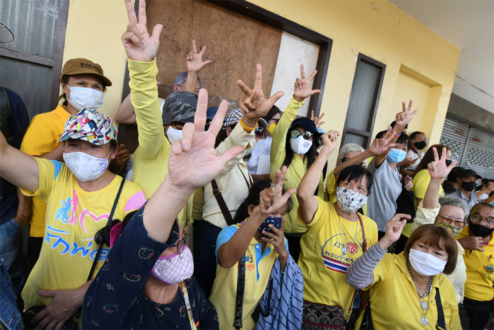 Protesters flash their version of the "three-finger salute," which they say represents the nation's three highest institutions: nation, religion and monarchy.