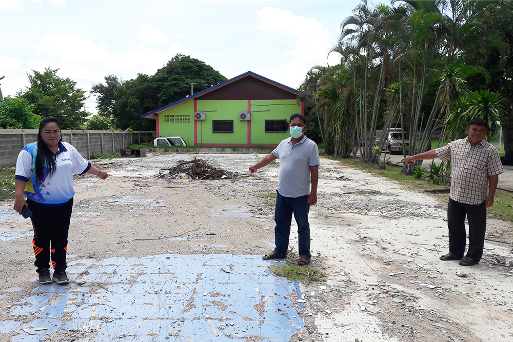 Teachers point at the ruins of the old building.