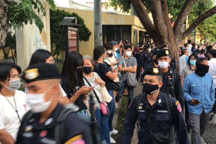 Riot police walk past protesters at an anti-government rally at the Democracy Monument on July 18, 2020.