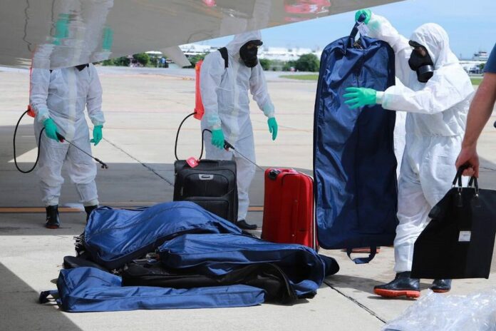 Airport workers on July 9, 2020, disinfect luggage carried on a plane carrying Chief of Staff of the U.S. Army Gen. James McConville to Thailand.