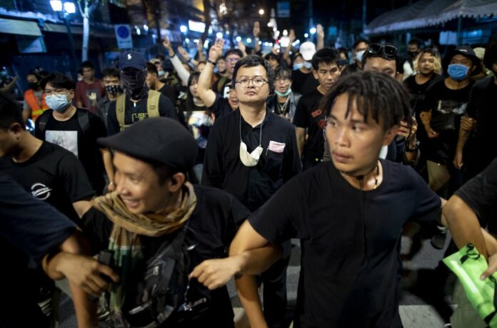 Pro-democracy activist and human rights lawyer Arnon Nampha, center, and student leaders walk to a police station in anticipation of arrest after a protest rally at Democracy Monument in Bangkok, Thailand, Sunday, Aug, 16, 2020. Photo: Gemunu Amarasinghe / AP