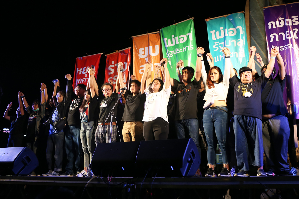 Activists raise their hands on stage at an anti-government rally on Aug. 16, 2020.