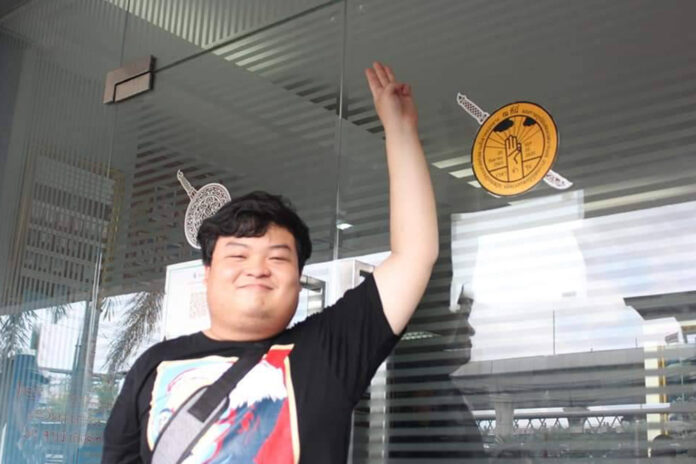 Activist Parit Chiwarak flashes a three-finger salute after placing “The People’s Party plaque” sticker onto the door of Bang Khen Police Station on Sept. 30, 2020.