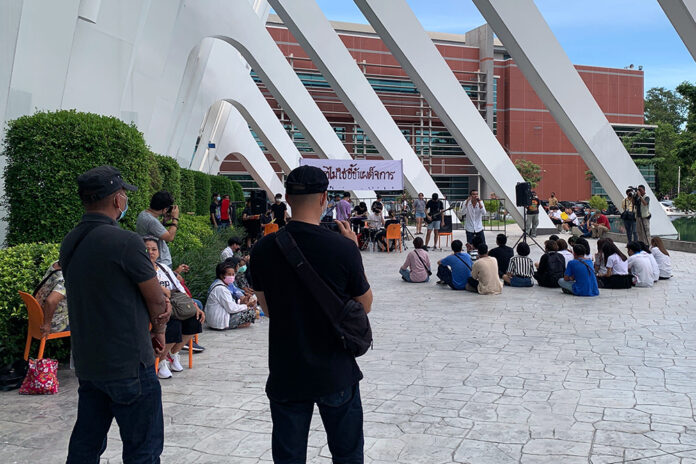 A man believed to be a plain-cloth police officer takes photo of an anti-government rally stage at Rangsit University on Sept. 2, 2020.