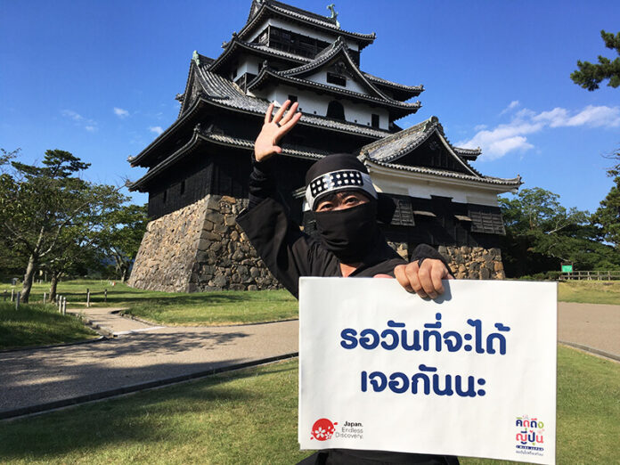 A ninja holds up a sign that reads, “Waiting for the day we meet again” at Matsue Castle in Shimane. Photo: Japan National Tourism Organization