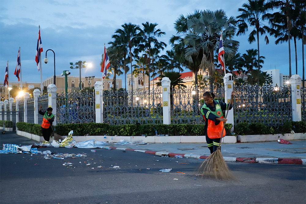 Workers sweep the street in front of the Government House.
