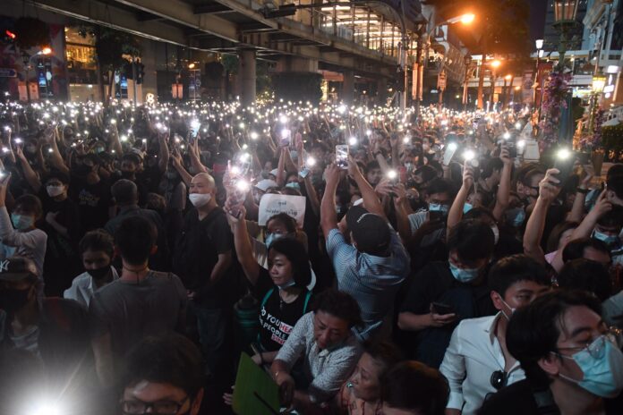 People hold up mobile phone flashlights at the anti-government protest at Ratchaprasong Intersection on Oct. 15, 2020.