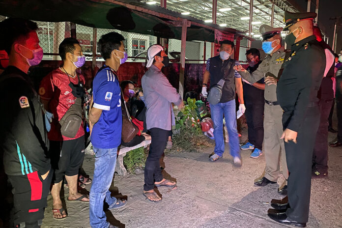 Security officials question a group of migrant workers left abandoned in front of a factory in Samut Prakan province on Dec. 22, 2020.