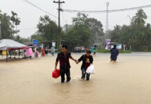 24 Died in Record Flood Ravaging Southern Provinces A couple braves a flooded road in Nakhon Si Thammarat province on Dec. 3, 2020.