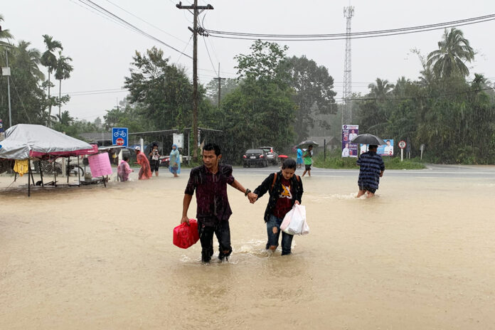 A couple braves a flooded road in Nakhon Si Thammarat province on Dec. 3, 2020. A couple braves a flooded road in Nakhon Si Thammarat province on Dec. 3, 2020.