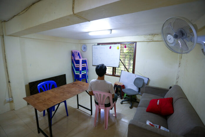 James sits in the living room, which regularly hosts English lessons for children in the community.