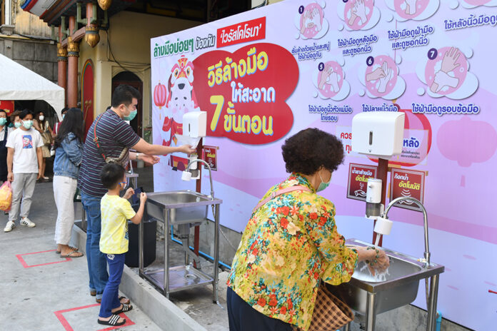 People wash hands before entering Wat Mangkon Kamalawat in Bangkok on Jan. 11, 2021.