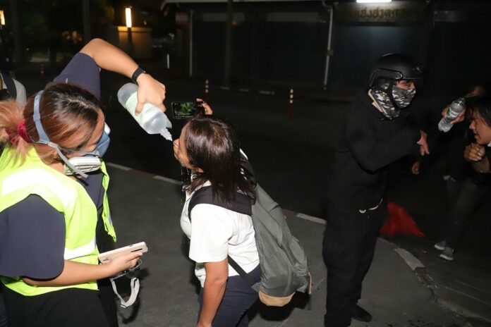 Reporters and demonstrators wash their faces after feeling the effect of tear gas during a clash on Feb. 10, 2021.