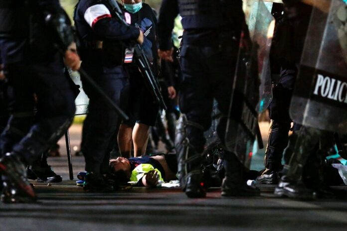 Volunteer medic Purapon Wongchiak, 19, lies on the ground after he was beaten by police near Sanam Luang on Feb. 13, 2021. Photo: Reuters Volunteer medic Purapon Wongchiak, 19, lies on the ground after he was beaten by police near Sanam Luang on Feb. 13, 2021. Photo: Reuters