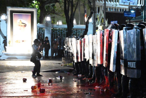 A photographer takes a photo during the clashes between anti-government protesters and police near the Grand Palace on Feb. 13, 2021.