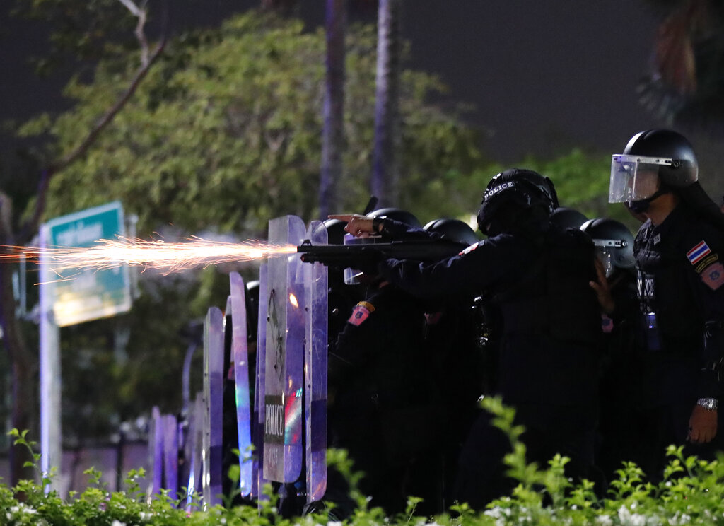 Sparks fly from the muzzle of a gun used by riot police to disperse protesters near the Grand Palace on Mar. 20, 2021. Photo: Sakchai Lalit / AP