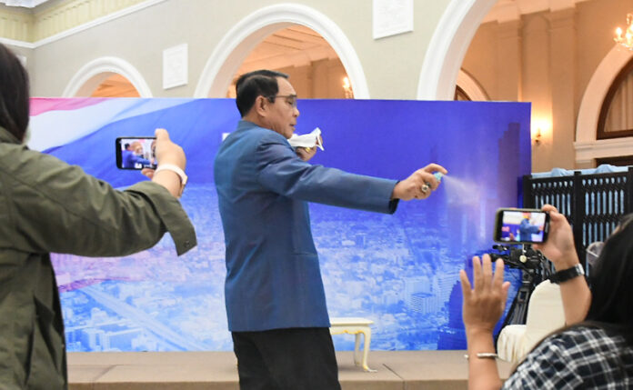 Gen. Prayut Chan-o-cha sprays reporters with sanitizer at Government House March 9, 2021.