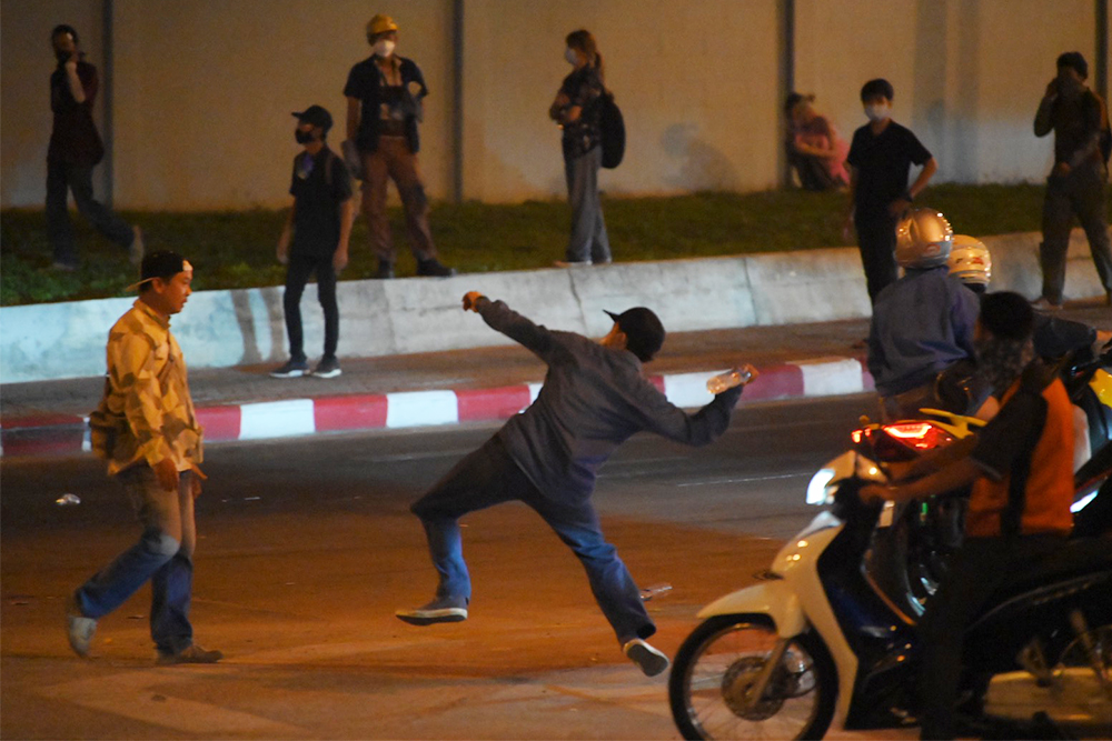 A protester throws a water bottle at riot police during the clash on Vibhavadi Rangsit Road.