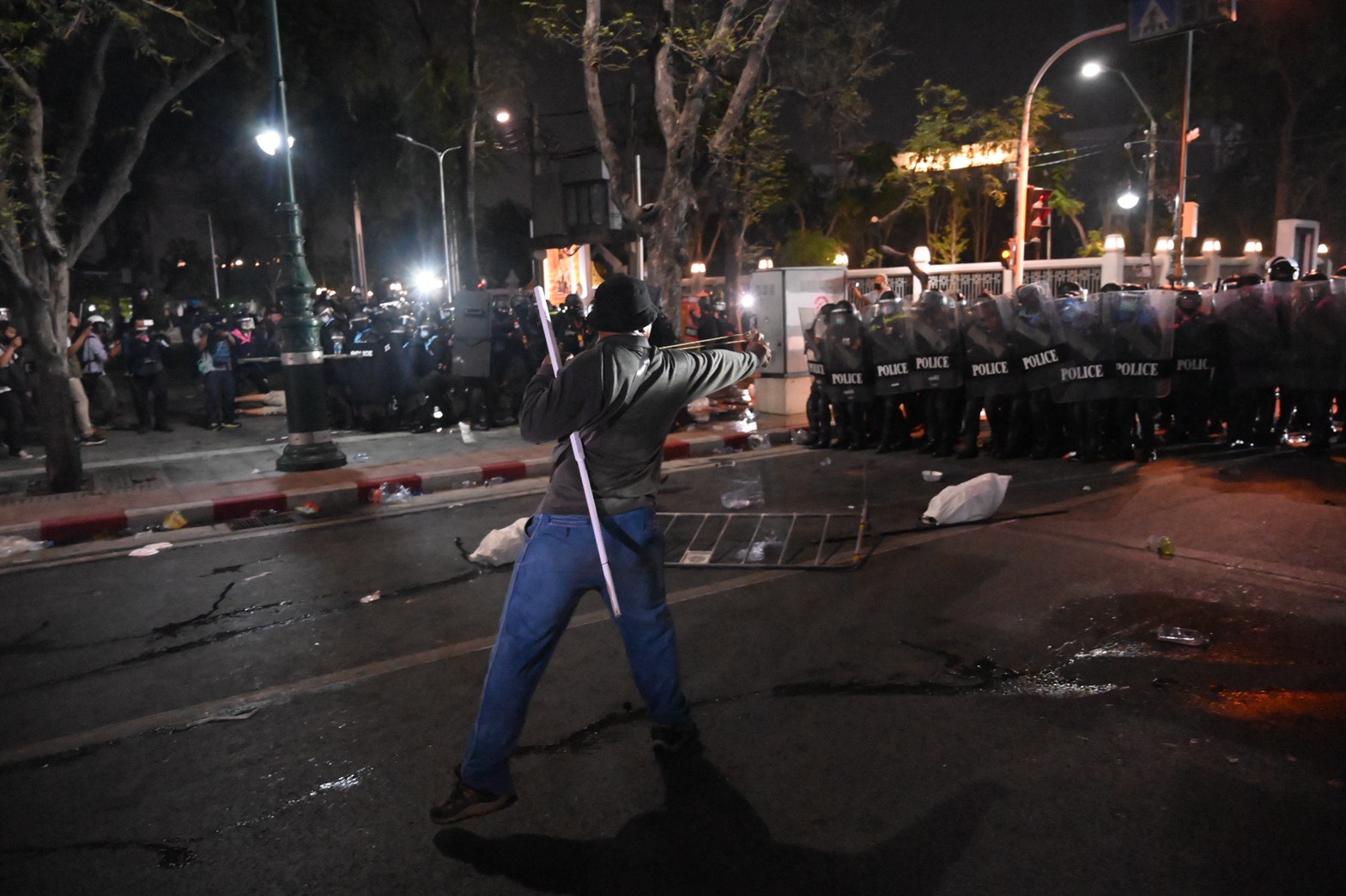 A protester fires a slingshot at riot police during the anti-government protest near the Grand Palace on Mar. 21, 2021.