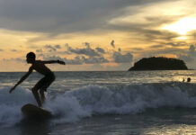 Thailand Reduces Quarantine, Paperwork for Vaccinated A surfer catches a wave as the sun sets over Kata Beach on the resort island of Phuket, Thailand on Sunday, May 26, 2019. Photo: Adam Schreck / AP