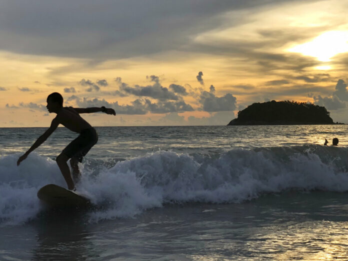 A surfer catches a wave as the sun sets over Kata Beach on the resort island of Phuket, Thailand on Sunday, May 26, 2019. Photo: Adam Schreck / AP