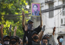 Myanmar Still Mired in Violence 2 Months After Military Coup Anti-coup demonstrators raise the three finger of resistance and a portrait of deposed leader Aung San Suu Kyi as prepare to confront police during a protest in Tarmwe township, Yangon, Myanmar, Thursday, April 1, 2021. Photo: AP