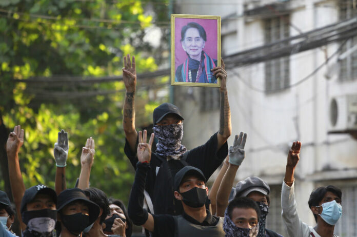 Anti-coup demonstrators raise the three finger of resistance and a portrait of deposed leader Aung San Suu Kyi as prepare to confront police during a protest in Tarmwe township, Yangon, Myanmar, Thursday, April 1, 2021. Photo: AP