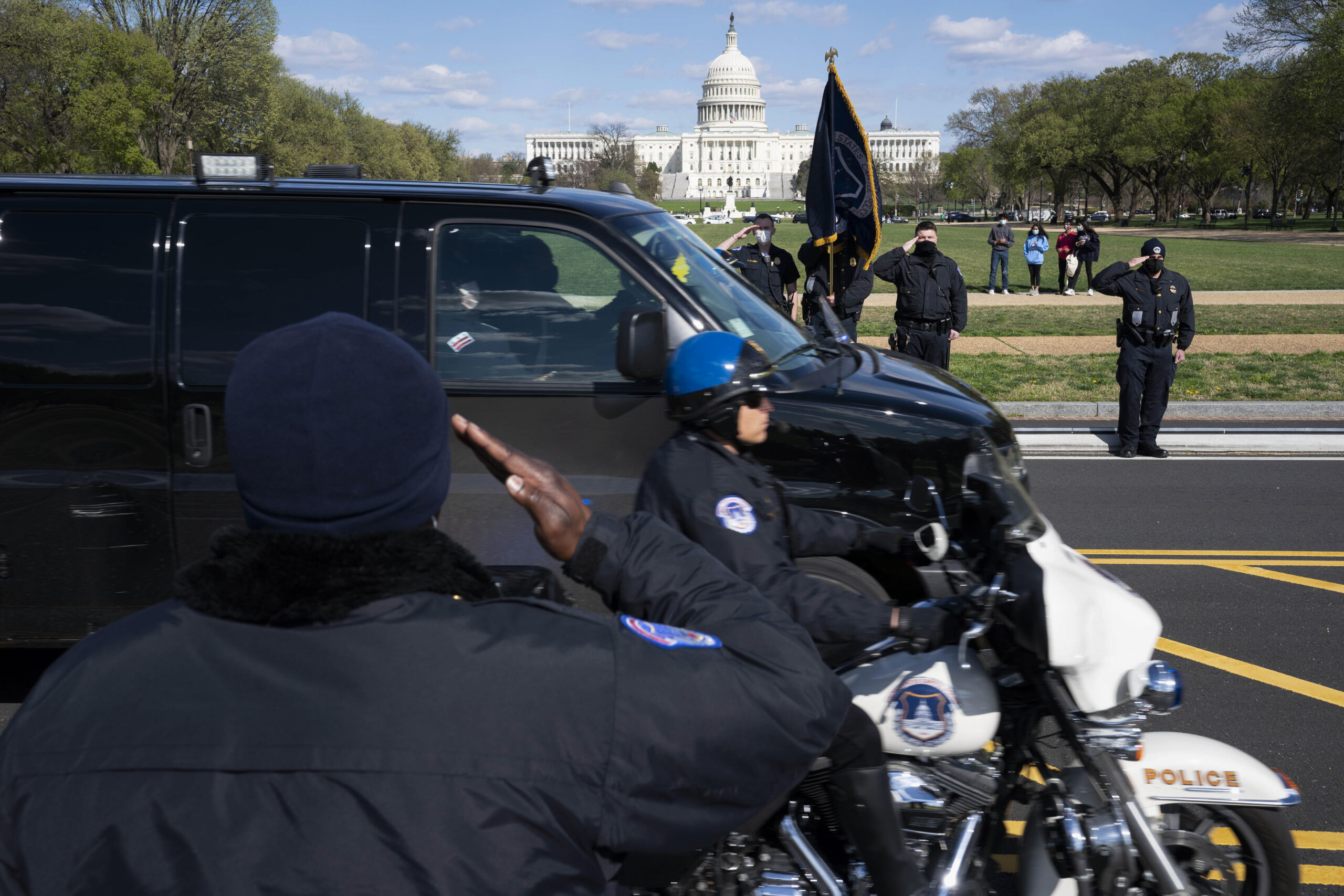 With the U.S. Capitol in the background, U.S. Capitol Police officers salute as procession carries the remains of a U.S. Capitol Police officer who was killed after a man rammed a car into two officers at a barricade outside the Capitol in Washington, Friday, April 2, 2021. Photo: Jose Luis Magana / AP