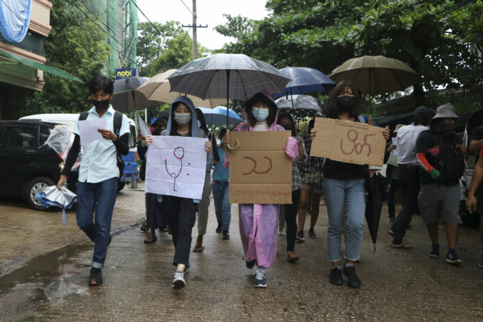 Anti-coup protesters hold slogans which read 