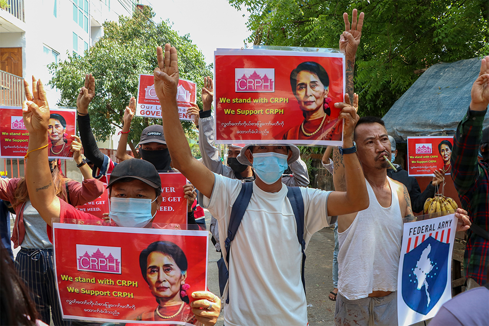 Anti-coup protesters flash the three-fingered symbol of resistance while holding slogans bearing pictures of deposed leader Aung San Suu Kyi during a demonstration in Yangon, Myanmar on Wednesday April 7, 2021. Photo: AP
