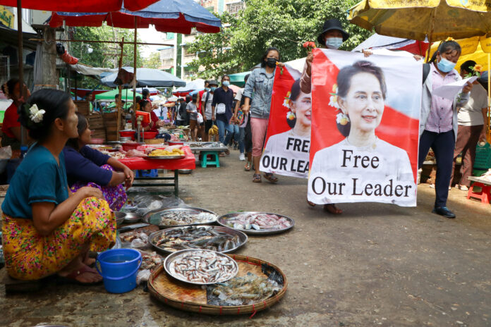 Anti-coup protesters walk through a market with images of ousted Myanmar leader Aung San Suu Kyi at Kamayut township in Yangon, Myanmar Thursday, April 8, 2021. Photo: AP Anti-coup protesters walk through a market with images of ousted Myanmar leader Aung San Suu Kyi at Kamayut township in Yangon, Myanmar Thursday, April 8, 2021. Photo: AP