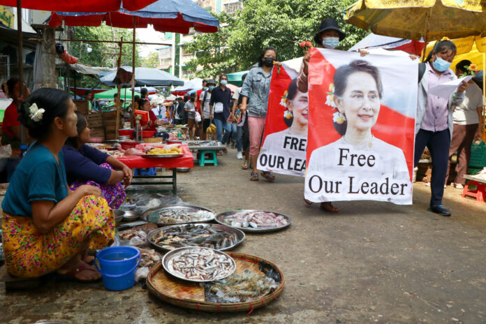 Anti-coup protesters walk through a market with images of ousted Myanmar leader Aung San Suu Kyi at Kamayut township in Yangon, Myanmar Thursday, April 8, 2021. Photo: AP Anti-coup protesters walk through a market with images of ousted Myanmar leader Aung San Suu Kyi at Kamayut township in Yangon, Myanmar Thursday, April 8, 2021. Photo: AP
