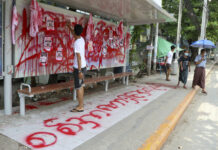 Myanmar Charges Doctors Over Civil Disobedience Protests An anti-coup protester uses red paint as he writes slogans at a bus stop on Wednesday April 14, 2021 in Yangon, Myanmar. Photo: AP