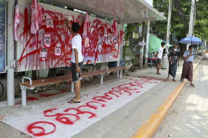 An anti-coup protester uses red paint as he writes slogans at a bus stop on Wednesday April 14, 2021 in Yangon, Myanmar. Photo: AP