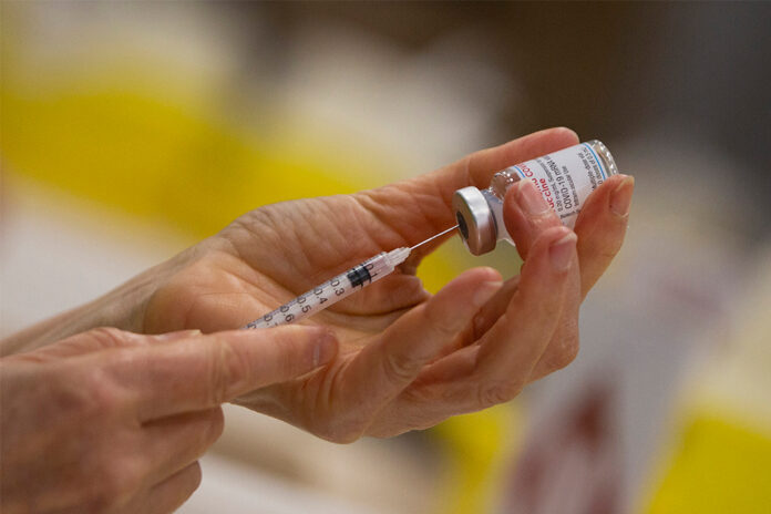 In this Wednesday, April 14, 2021 file photo, a pharmacist fills a syringe from a vial of the Moderna COVID-19 vaccine in Antwerp, Belgium. Photo: Virginia Mayo / AP