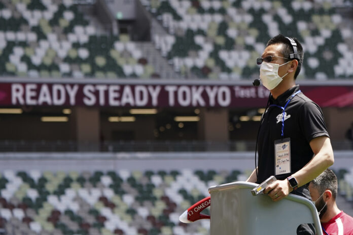 An official wears a face mask as he uses a starter pistol to signal the start a women's 100 meter heat at an athletics test event for the Tokyo 2020 Olympics Games at National Stadium in Tokyo, Sunday, May 9, 2021. Photo: Shuji Kajiyama / AP An official wears a face mask as he uses a starter pistol to signal the start a women's 100 meter heat at an athletics test event for the Tokyo 2020 Olympics Games at National Stadium in Tokyo, Sunday, May 9, 2021. Photo: Shuji Kajiyama / AP