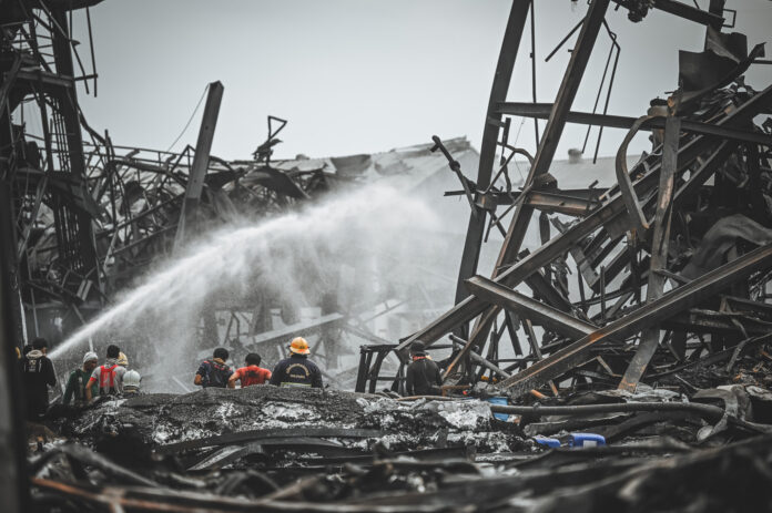 Firefighters spray foam amid twisted metal frames of a charred chemical factory Tuesday, July 6, 2021 in Samut Prakan, Thailand.