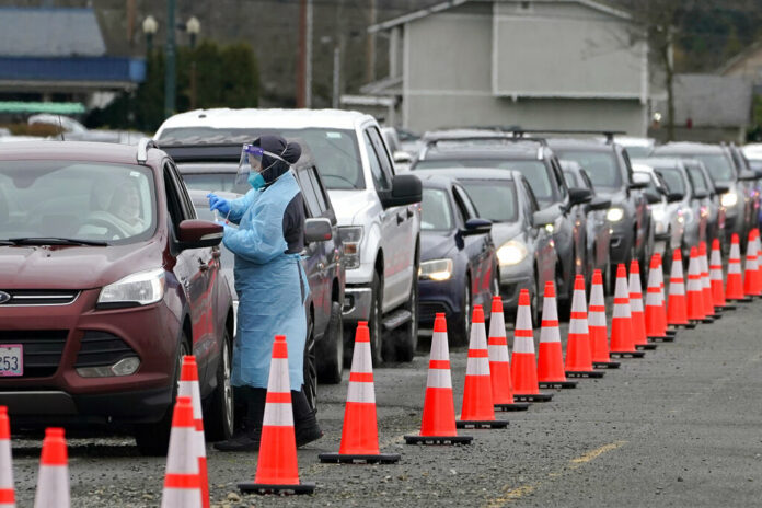 A worker at a drive-up COVID-19 testing clinic administers PCR coronavirus tests, Tuesday, Jan. 4, 2022, in Puyallup, Wash., south of Seattle. Photo: Ted S. Warren / AP A worker at a drive-up COVID-19 testing clinic administers PCR coronavirus tests, Tuesday, Jan. 4, 2022, in Puyallup, Wash., south of Seattle. Photo: Ted S. Warren / AP